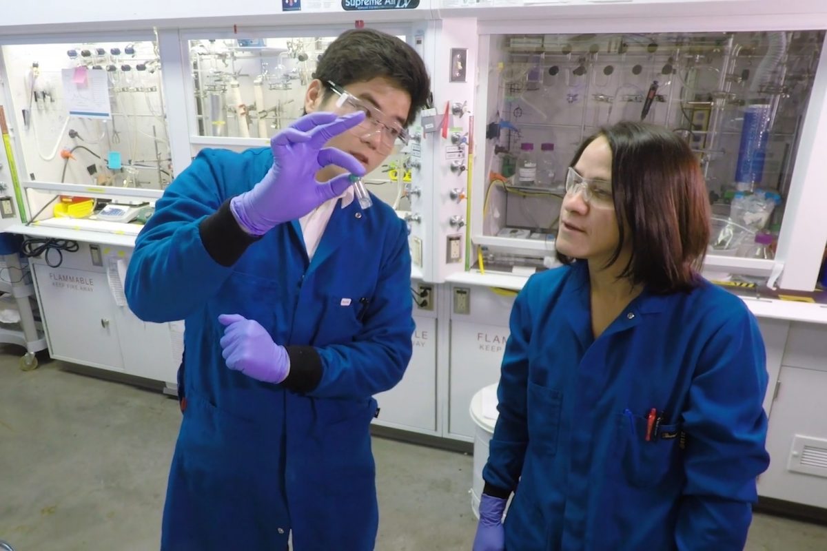 Two scientists in a lab look at a test tube 