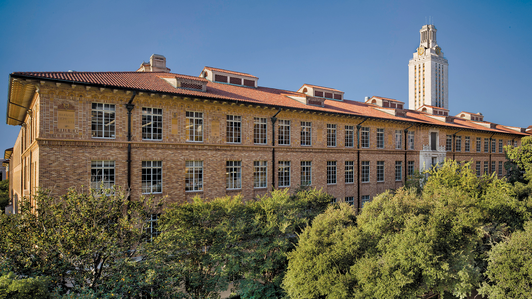 view of an orange brick building with a tower in the background